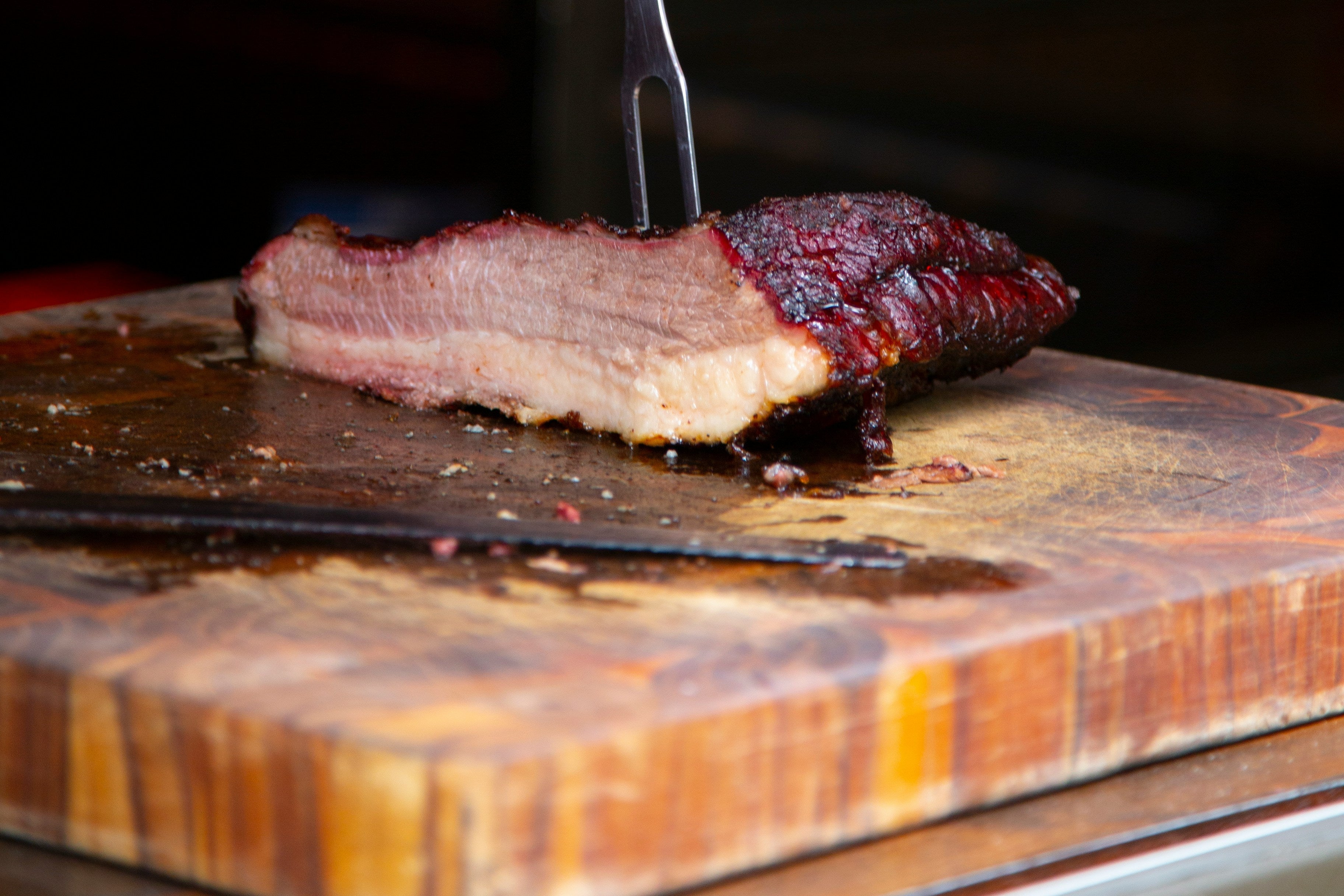 Sliced barbecue on a wooden cutting board with a knife, blurred background